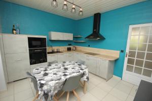 une cuisine avec une table et un mur bleu dans l'établissement Maison de caractère Caprice Normand, jardin clos, 7min à pied des plages, à Langrune-sur-Mer