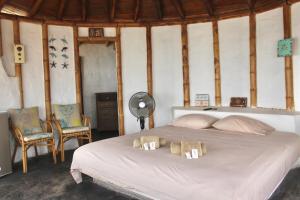 a bedroom with a bed with two chairs and a fan at Marina Bungalows in Los Órganos +37 photos