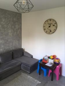 uma sala de estar com um sofá e um relógio na parede em Apartament Szpitalna em Suwałki