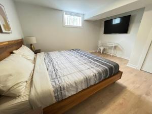 a bedroom with a bed and a television on the wall at Letitia Heights !A Spacious and Quiet Private Bedroom with Shared Bathroom in Barrie