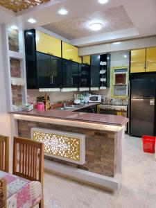 a large kitchen with black and yellow cabinets at فيلا للايجار في مارينا 4 حمام سباحة خاص in El Alamein