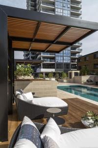 a patio with a couch and a swimming pool at Burleigh Beach Escape with Stunning Sunset Views in Gold Coast