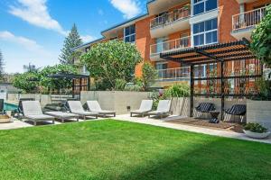 a patio with chairs and a lawn in front of a building at Burleigh Beach Escape with Stunning Sunset Views in Gold Coast