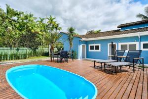 a deck with a pool and a table and chairs at Casa Caminho da Praia 3 quartos com ar no Cabore in Paraty