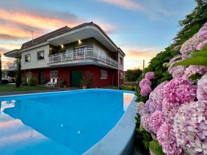 a house with a swimming pool and pink flowers at Camino del Soplao -zona Santillana del Mar- in Reocín