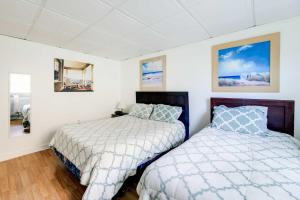 2 camas en un dormitorio con paredes blancas y suelo de madera en Hannahs Place - Quaint and Cozy Apt by the Beach! en Emerald Isle