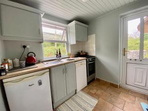 a small kitchen with white cabinets and a window at Oranuisce Thatch Cottage Ballyvaughan in Ballyvaughan