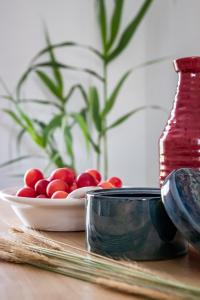 una mesa con un bol de fruta roja y un jarrón en Yianna Sunny Studios, en Skopelos Town