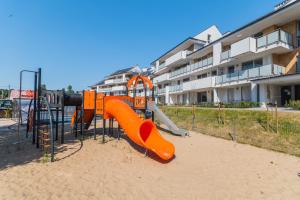 a playground with an orange slide in front of a building at Apartament Mierzeja LUX Baltic Garden in Sztutowo
