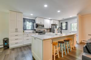 a kitchen with white cabinets and bar stools at Pasadena Hideaway with Game Room and Fire Pit! in Glen Burnie