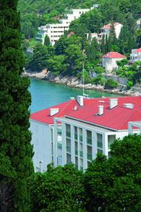 a building with a red roof next to a body of water at Dubrovnik Luxury Residence – L’Orangerie in Dubrovnik