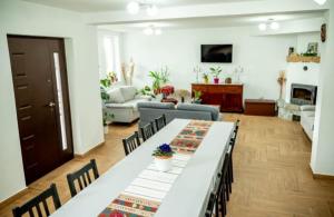 a living room with a long table and chairs at Pensiunea Rozelor Stațiunea Climaterică Sâmbăta in Sâmbăta de Sus