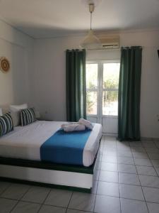 a bedroom with a bed with green curtains and a window at Angistri's panorama apartments in Skala