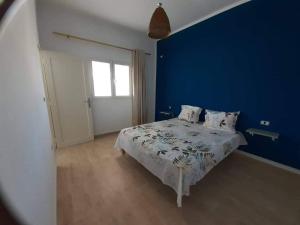 a blue bedroom with a bed and a blue wall at Résidence de la plage Ghar El Melh in Ghār al Milḩ