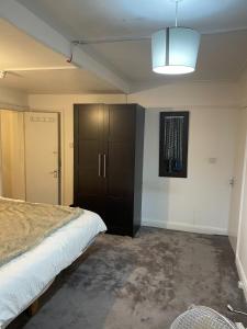 a bedroom with a bed and a black cabinet at Edgware Rooms in Stone Grove