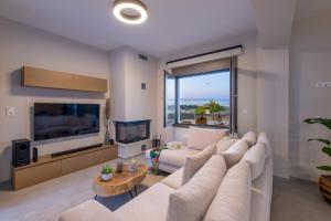 sala de estar con un gran sofá blanco y TV en Leon Luxury Home in Rethymno en Gállos