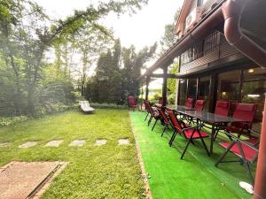 patio z czerwonymi krzesłami i stołem na trawniku w obiekcie Best of Ilidza and Rakovica holiday HOME w Sarajewie