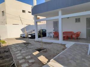 a white house with a table and chairs and a car at Résidence de la plage Ghar El Melh in Ghār al Milḩ