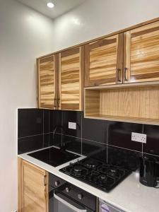 a kitchen with a stove and wooden cabinets at MCM _Haven in Dar es Salaam
