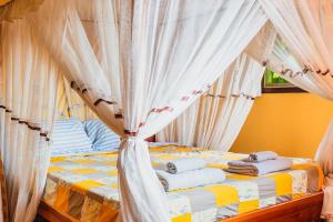 Una cama con cortinas blancas y toallas. en Aparthotel Jardin Tropical, en Buyumbura