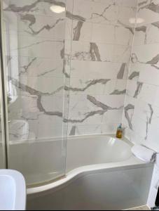 a white bath tub in a bathroom with marble walls at Adina s House in Rugeley