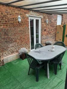 a patio with a table and chairs and a brick wall at Gîte du bonheur 