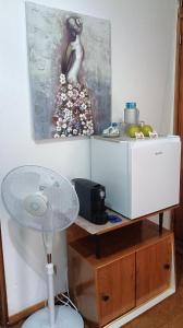 a desk with a fan and a painting on the wall at Alojamento Local Largo da Igreja in Santiago do Cacém