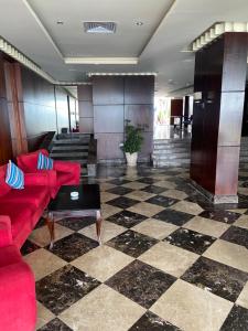 um átrio com sofás vermelhos e um piso xadrez em Executive Royal Tower Apartments - Sky Lounge em El Alamein