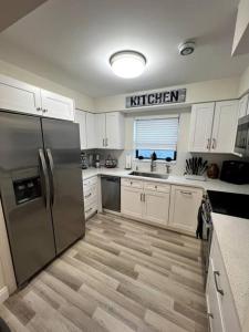 uma cozinha com armários brancos e um frigorífico de aço inoxidável em Modern Tropical Oasis with Arcade, HotTub & MiniGolf em Hollywood