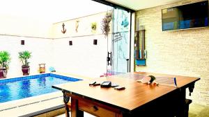 a ping pong table in a room with a swimming pool at Piscina com ofurô/Churrasqueira/Sinuca e Ping Pong in Caraguatatuba