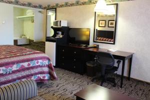 Habitación de hotel con cama, escritorio y espejo. en Safari Inn, en Limon