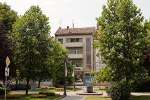 un gran edificio con árboles delante de él en Treetop Apartments en Vršac