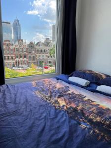 a bed with a view of a city from a window at MyCityLofts in Rotterdam