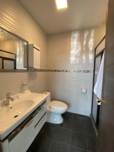 ein Badezimmer mit einem Waschbecken, einem WC und einem Spiegel in der Unterkunft Suites AlojaT MIMOS Machala diagonal al oro verde. in Machala