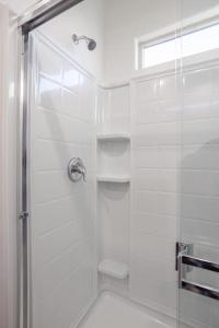 a white bathroom with a shower with a glass door at MM house in Marana