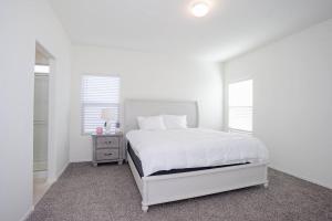 a white bedroom with a white bed and two windows at MM house in Marana