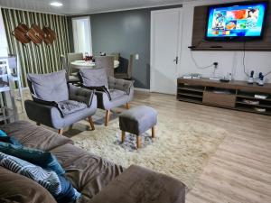 a living room with a couch and chairs and a tv at Refugio Por do Sol - 09 Pessoas - WiFi- Ar Condicionado in Gramado