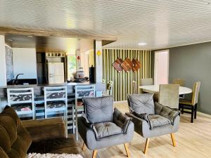a living room with two chairs and a kitchen at Refugio Por do Sol - 09 Pessoas - WiFi- Ar Condicionado in Gramado