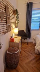 een slaapkamer met een tafel met een lamp en een stoel bij Bluebelle Lodge 