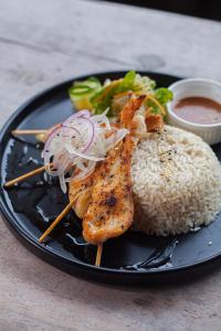 a black plate of food with rice and meat at Hotel Playa Cambutal in Cambutal