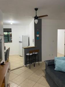 a living room with a couch and a kitchen with a ceiling fan at Ap 202 Hospedagem in Rio das Ostras
