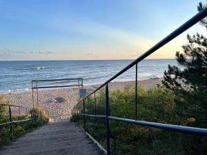 una escalera que conduce a una playa con el océano en Domek holenderski -noclegi, en Mielno
