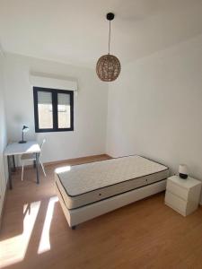 a white room with a bed and a table at Alojamento Moscavide - Aeroporto II in Lisbon