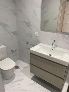 a white bathroom with a sink and a toilet at Alojamento Moscavide - Aeroporto II in Lisbon