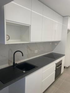 a kitchen with white cabinets and a black sink at Alojamento Moscavide - Aeroporto II in Lisbon