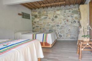 a bedroom with two beds and a stone wall at El jardín de la salud hotel in Fortín de las Flores