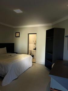 a bedroom with a bed and a door to a bathroom at Pousada e Restaurante Valle dos Ventos in Chapada dos Guimarães