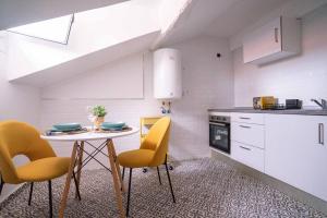 a kitchen with a table and yellow chairs in it at 10C02 Moderno ático en Pravia in Pravia