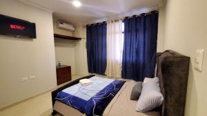 um quarto com uma cama e uma janela com cortinas azuis em Habitaciones AlojaT MIMOS diagonal al hotel oro verde em Machala