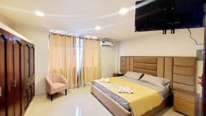 um quarto com uma cama, uma cadeira e uma televisão em Habitaciones AlojaT MIMOS diagonal al hotel oro verde em Machala